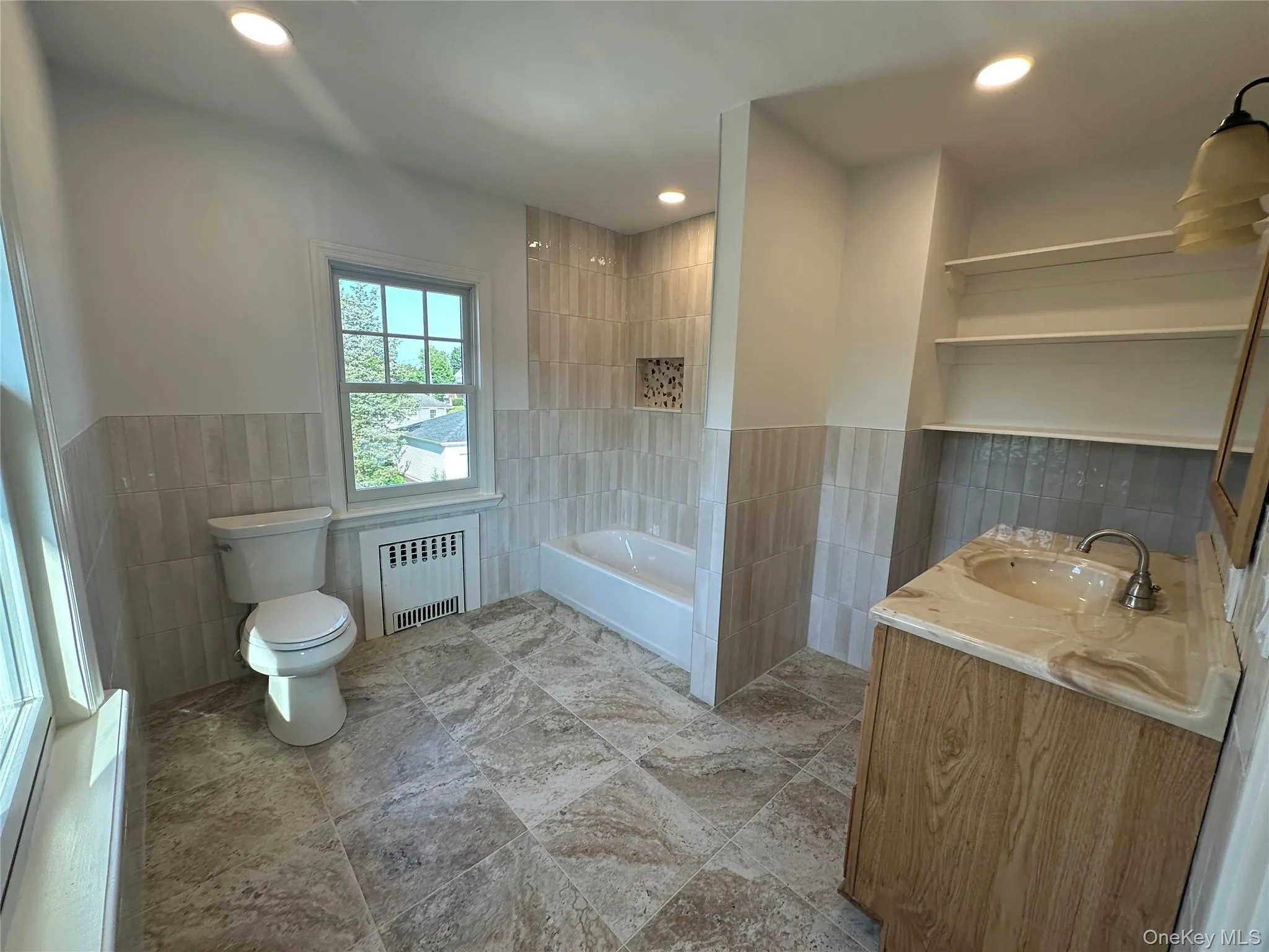 Bathroom featuring tile walls, wainscoting, vanity, radiator heating unit, and recessed lighting Bathroom featuring tile walls, wainscoting, vanity, radiator heating unit, and recessed lighting