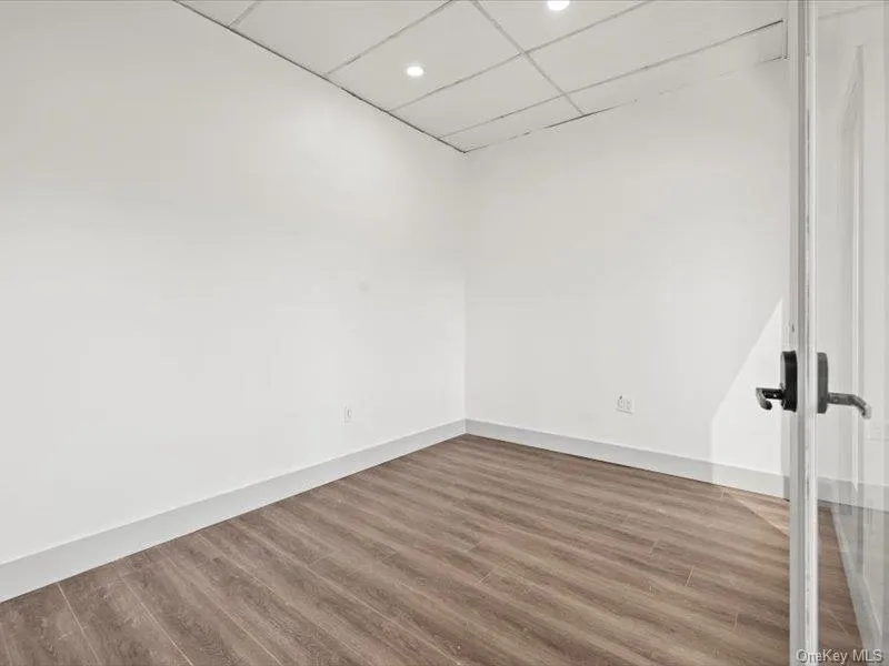 Unfurnished room with wood finished floors, a drop ceiling, and recessed lighting Unfurnished room with wood finished floors, a drop ceiling, and recessed lighting