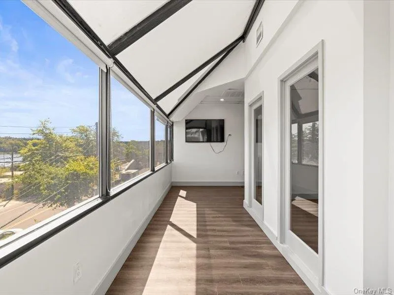 Unfurnished sunroom with wood finished floors and vaulted ceiling Unfurnished sunroom with wood finished floors and vaulted ceiling