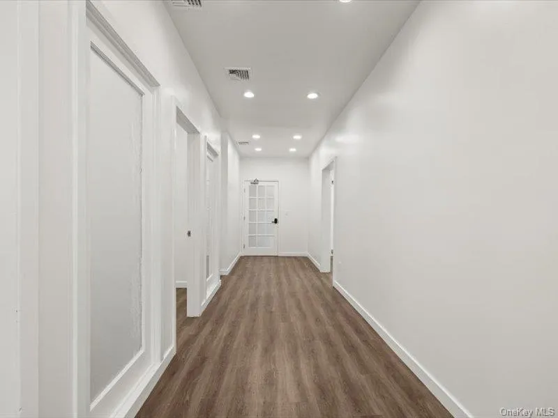Hallway with recessed lighting and dark wood-style flooring Hallway with recessed lighting and dark wood-style flooring