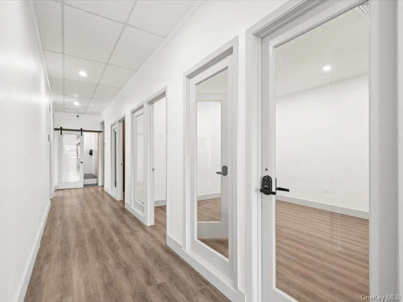 Hallway with a barn door, wood finished floors, a paneled ceiling, and recessed lighting Hallway with a barn door, wood finished floors, a paneled ceiling, and recessed lighting
