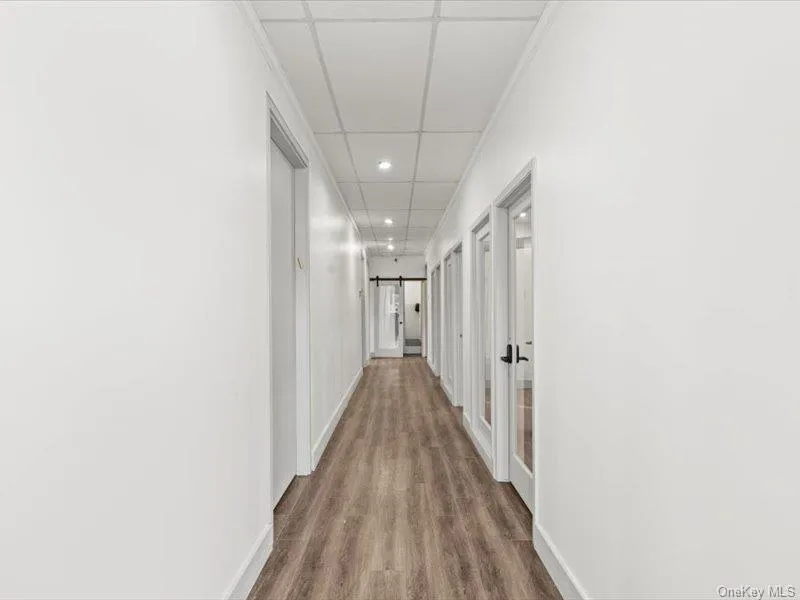 Corridor with recessed lighting, a barn door, dark wood-type flooring, and a drop ceiling Corridor with recessed lighting, a barn door, dark wood-type flooring, and a drop ceiling