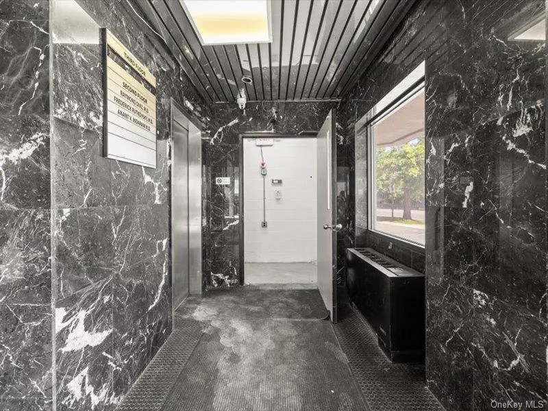 Corridor featuring elevator and tile walls Corridor featuring elevator and tile walls