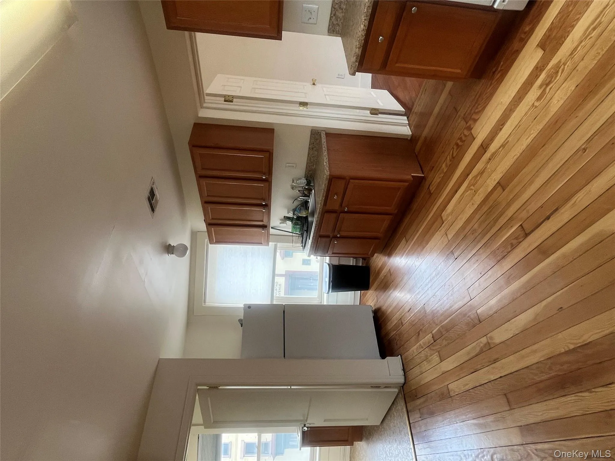 Kitchen with brown cabinetry, fridge, and light wood finished floors Kitchen with brown cabinetry, fridge, and light wood finished floors
