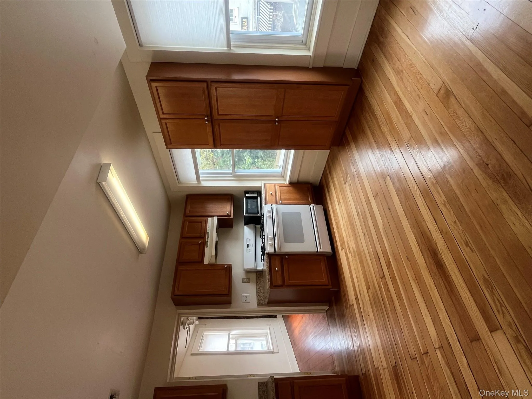 Kitchen featuring brown cabinetry, stove, plenty of natural light, and light wood-style floors Kitchen featuring brown cabinetry, stove, plenty of natural light, and light wood-style floors