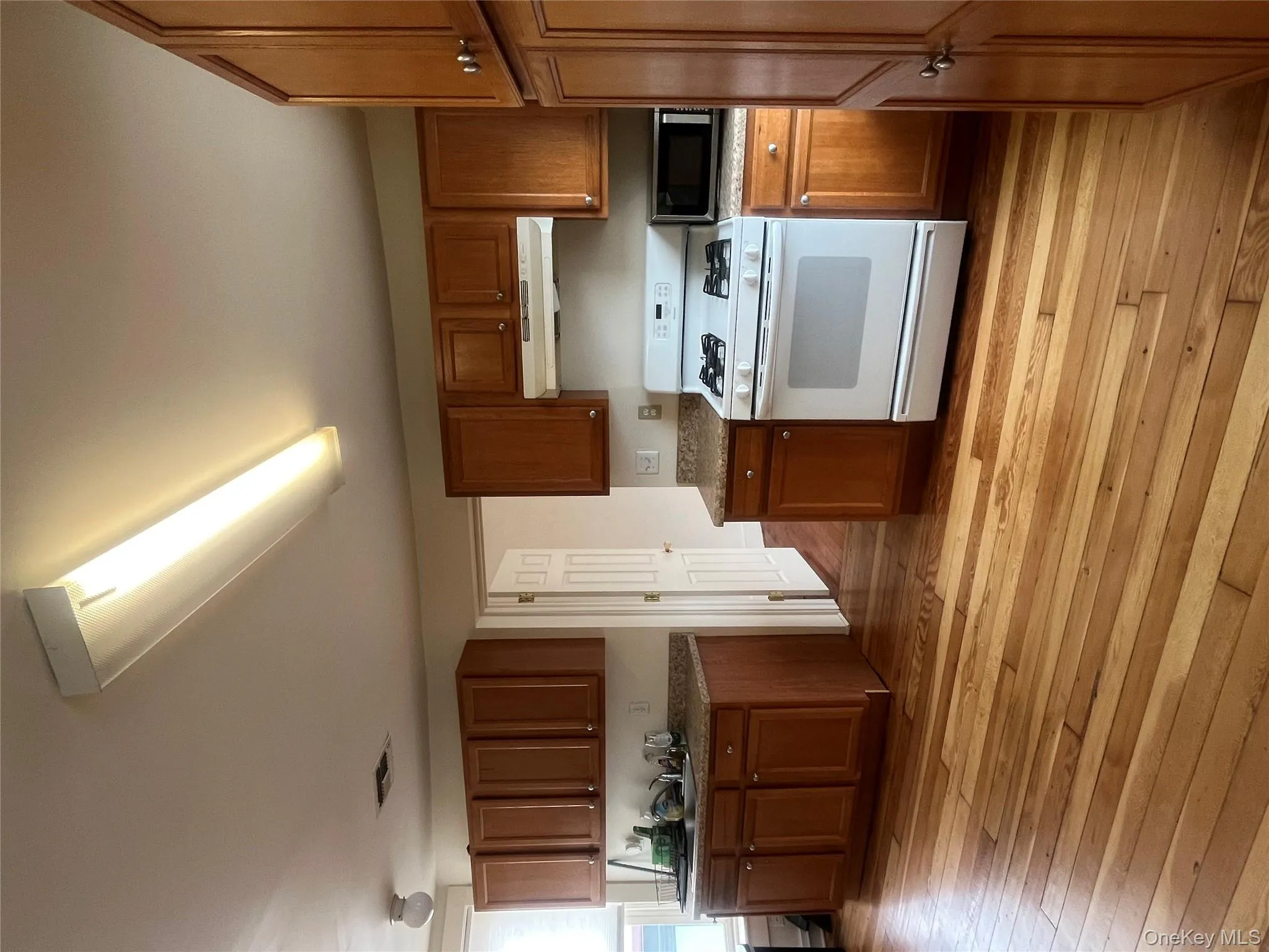 Kitchen with stove, brown cabinets, light wood-style flooring, and extractor fan Kitchen with stove, brown cabinets, light wood-style flooring, and extractor fan