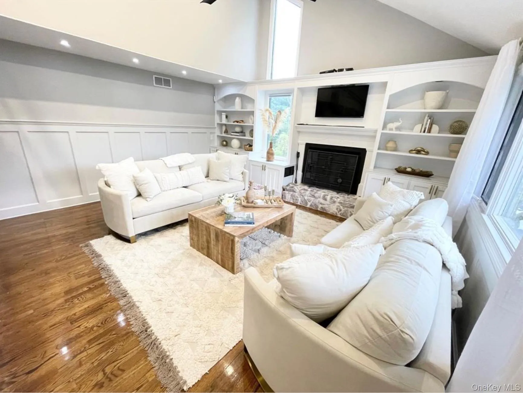 Living area featuring wood finished floors, high vaulted ceiling, a glass covered fireplace, a decorative wall, and recessed lighting Living area featuring wood finished floors, high vaulted ceiling, a glass covered fireplace, a decorative wall, and recessed lighting