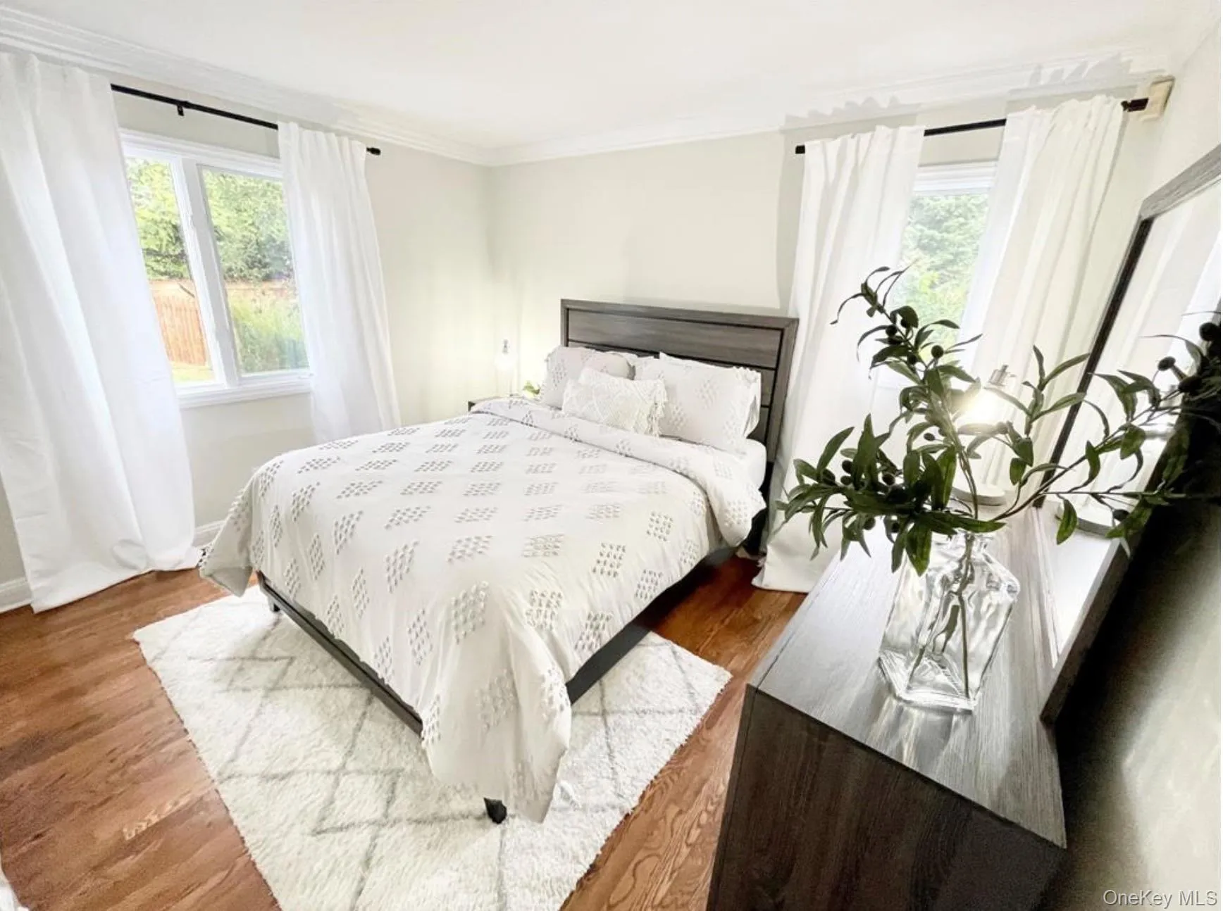 Bedroom with multiple windows, wood finished floors, and ornamental molding Bedroom with multiple windows, wood finished floors, and ornamental molding