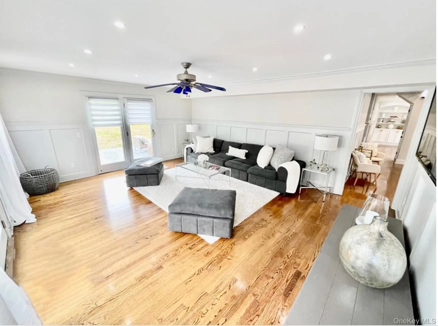Living area featuring a decorative wall, wood finished floors, wainscoting, recessed lighting, and a ceiling fan Living area featuring a decorative wall, wood finished floors, wainscoting, recessed lighting, and a ceiling fan