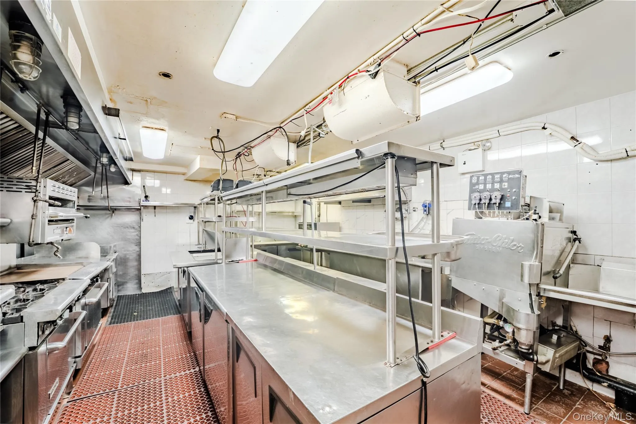 Kitchen featuring stainless steel countertops, dark tile patterned flooring, and stainless steel gas stove Kitchen featuring stainless steel countertops, dark tile patterned flooring, and stainless steel gas stove