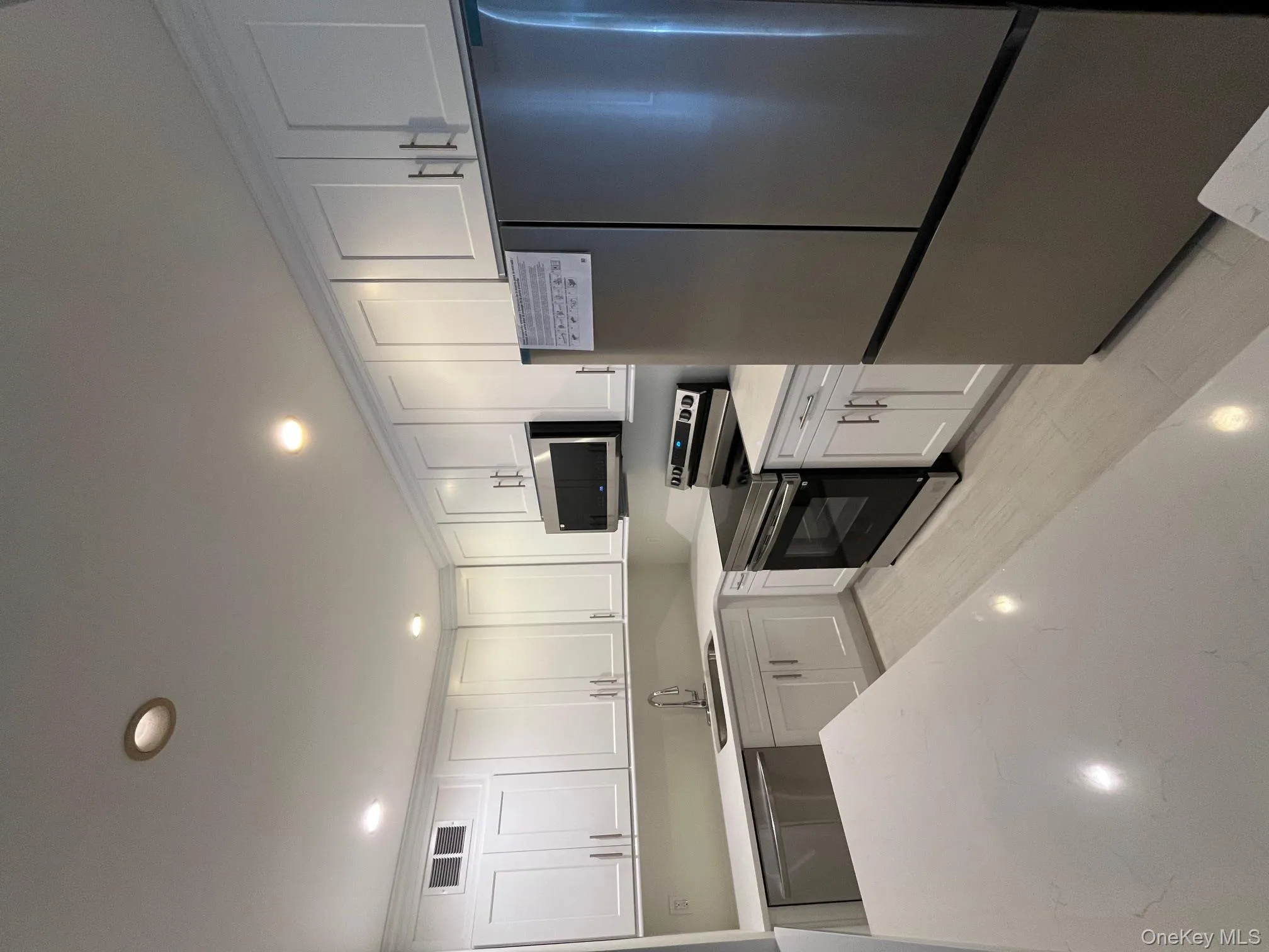 Kitchen with appliances with stainless steel finishes, recessed lighting, white cabinetry, light stone countertops, and light wood-style flooring Kitchen with appliances with stainless steel finishes, recessed lighting, white cabinetry, light stone countertops, and light wood-style flooring