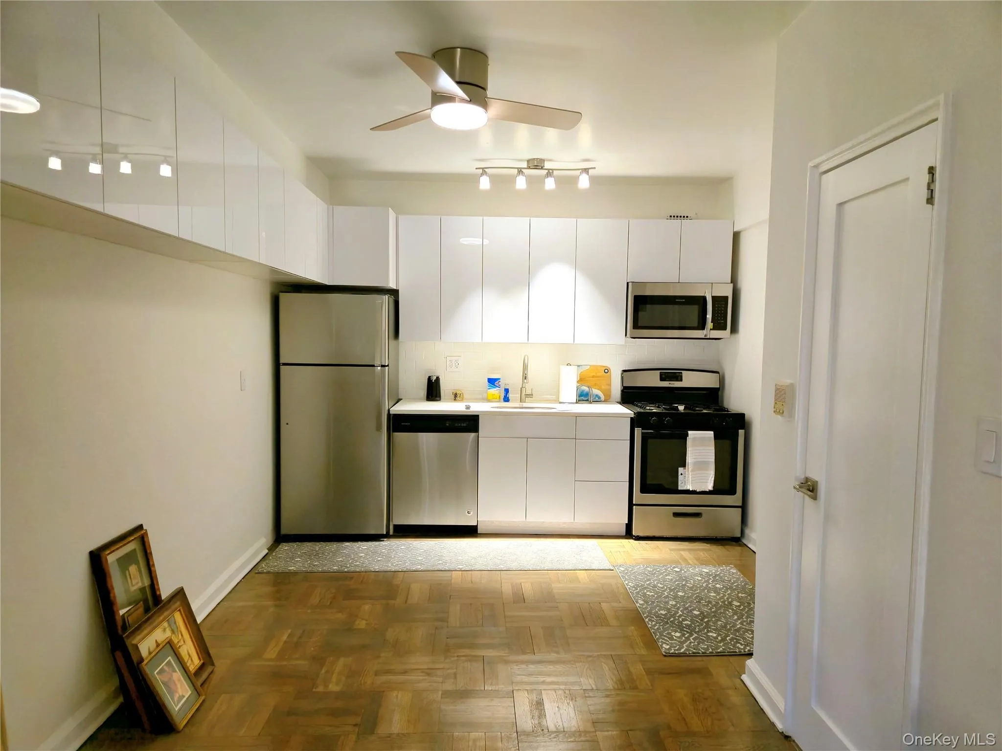 Kitchen featuring white cabinets, baseboards, a sink, appliances with stainless steel finishes, and a ceiling fan Kitchen featuring white cabinets, baseboards, a sink, appliances with stainless steel finishes, and a ceiling fan