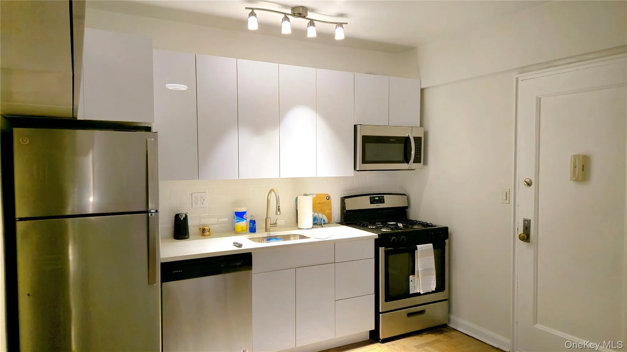 Kitchen with white cabinets, light countertops, a sink, stainless steel appliances, and backsplash Kitchen with white cabinets, light countertops, a sink, stainless steel appliances, and backsplash