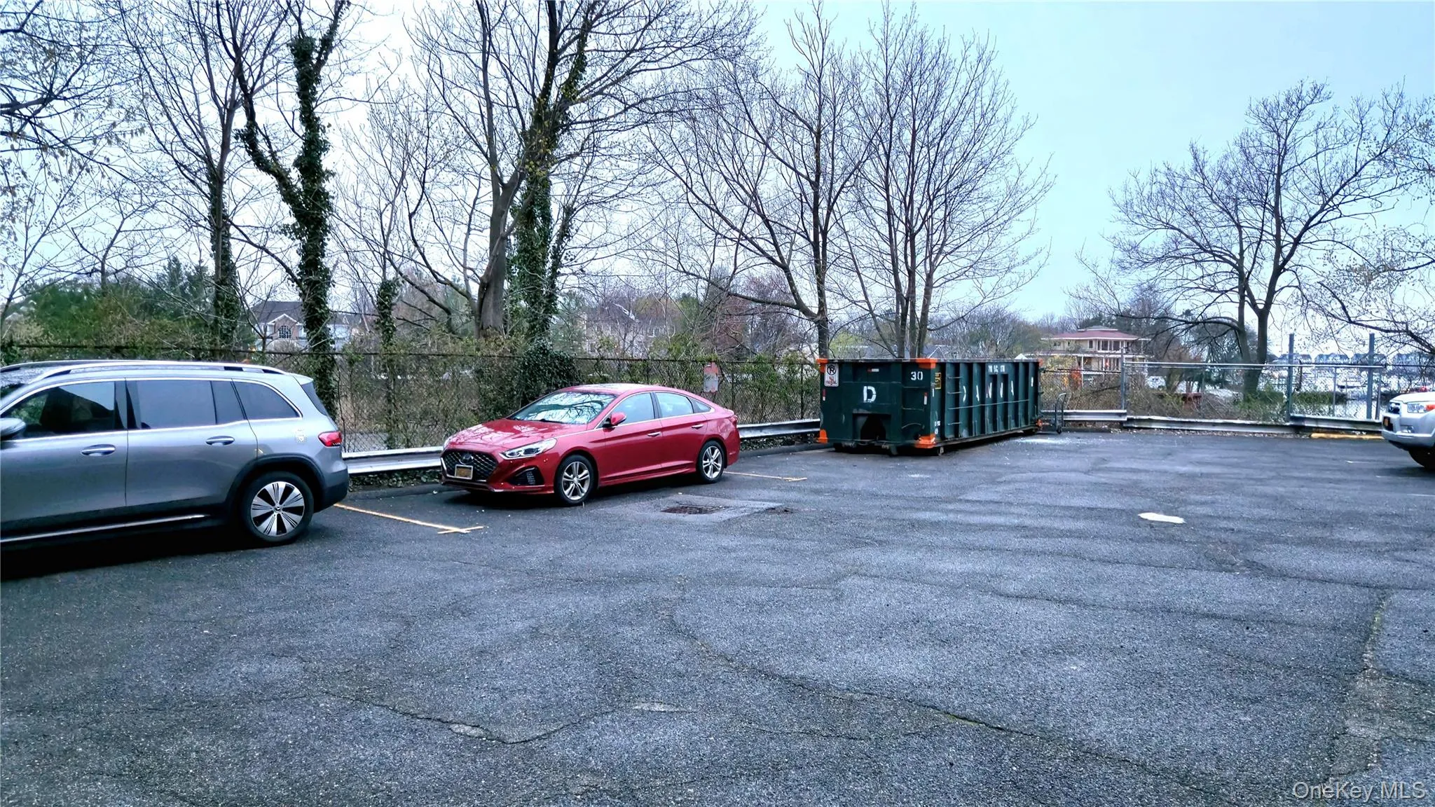 Uncovered parking lot featuring fence Uncovered parking lot featuring fence