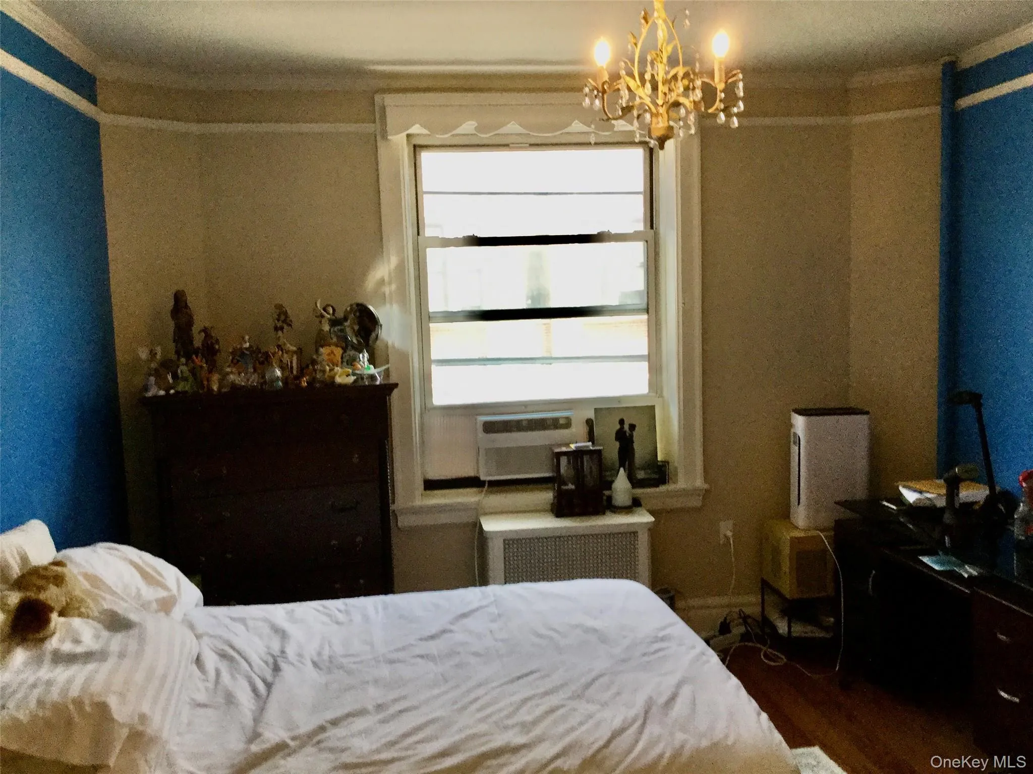 Bedroom featuring dark wood-style flooring, radiator heating unit, and a chandelier Bedroom featuring dark wood-style flooring, radiator heating unit, and a chandelier