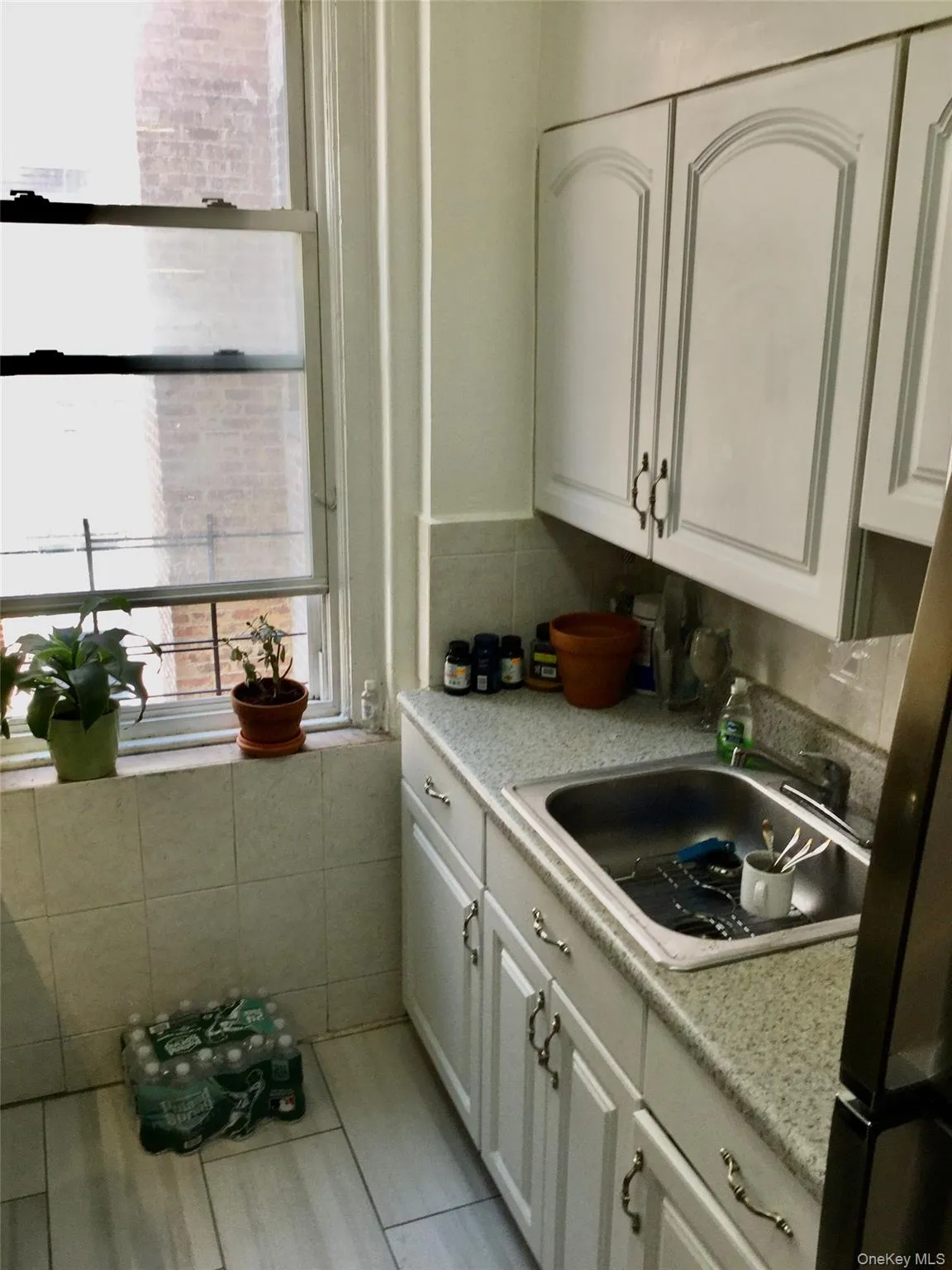 Kitchen featuring white cabinets, light countertops, and backsplash Kitchen featuring white cabinets, light countertops, and backsplash