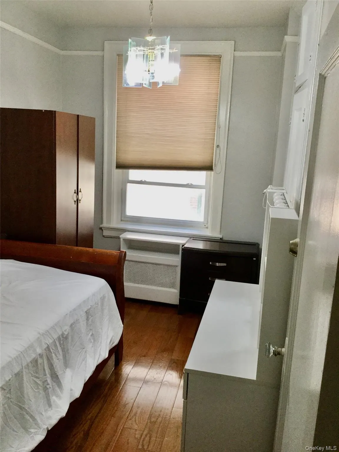 Bedroom with dark wood-style flooring, radiator, and a chandelier Bedroom with dark wood-style flooring, radiator, and a chandelier