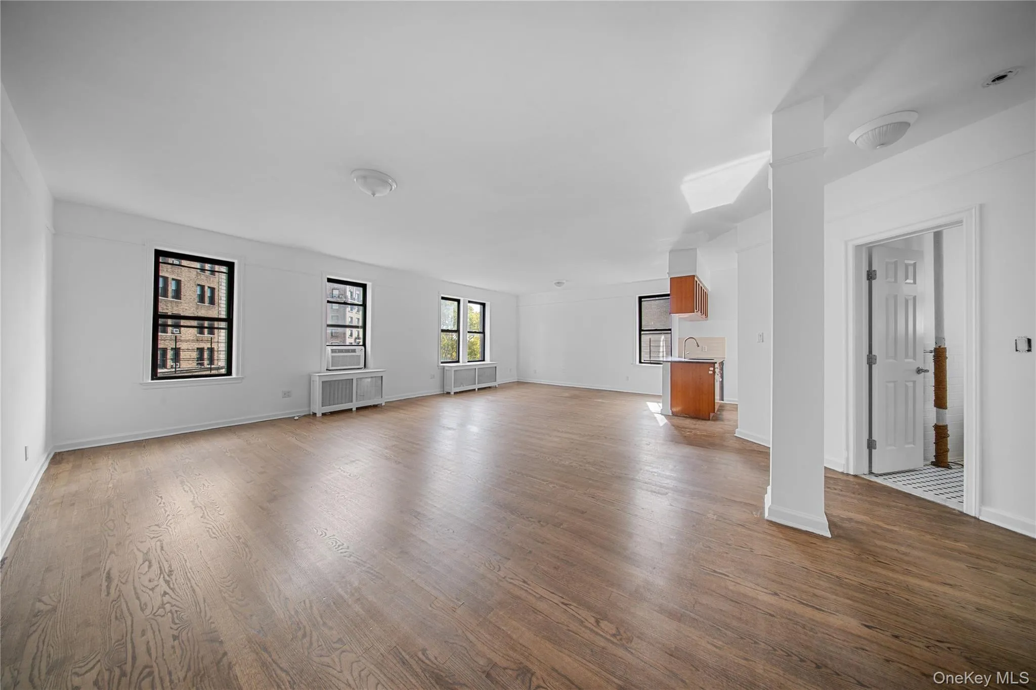 Unfurnished living room featuring wood finished floors and radiator Unfurnished living room featuring wood finished floors and radiator