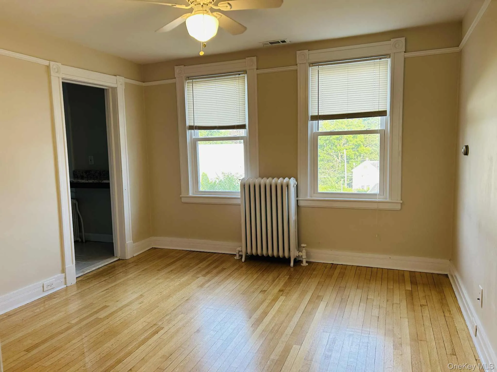 Living room featuring radiator, light wood-style flooring, and a ceiling fan Living room featuring radiator, light wood-style flooring, and a ceiling fan