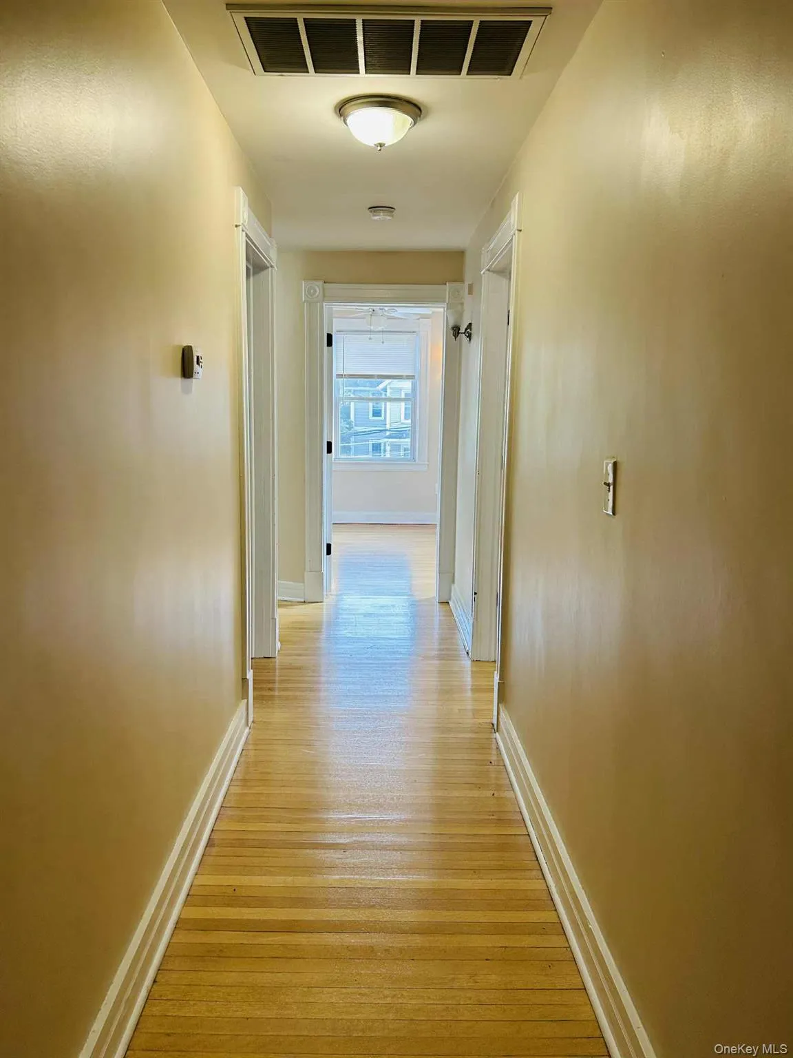 Hallway featuring baseboards and light wood finished floors Hallway featuring baseboards and light wood finished floors