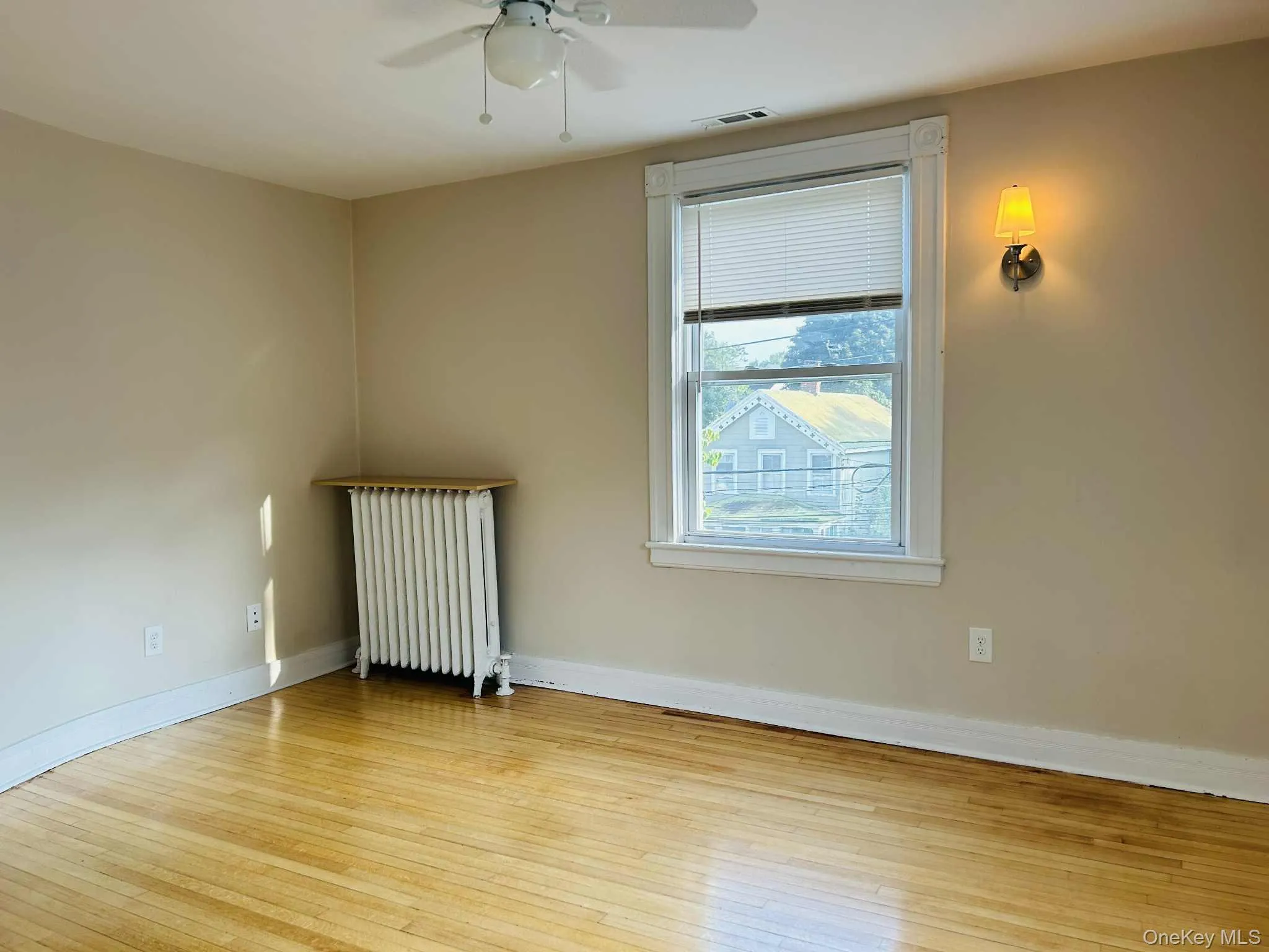Bedroom with radiator, light wood-style floors, and ceiling fan Bedroom with radiator, light wood-style floors, and ceiling fan