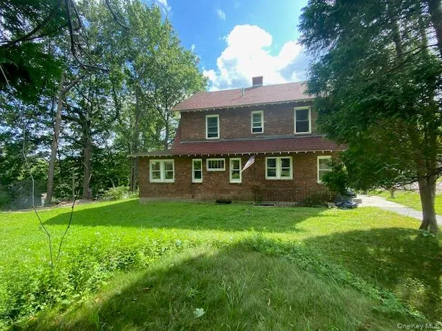 View of front of house featuring a front yard, brick siding, a shingled roof, and a chimney View of front of house featuring a front yard, brick siding, a shingled roof, and a chimney