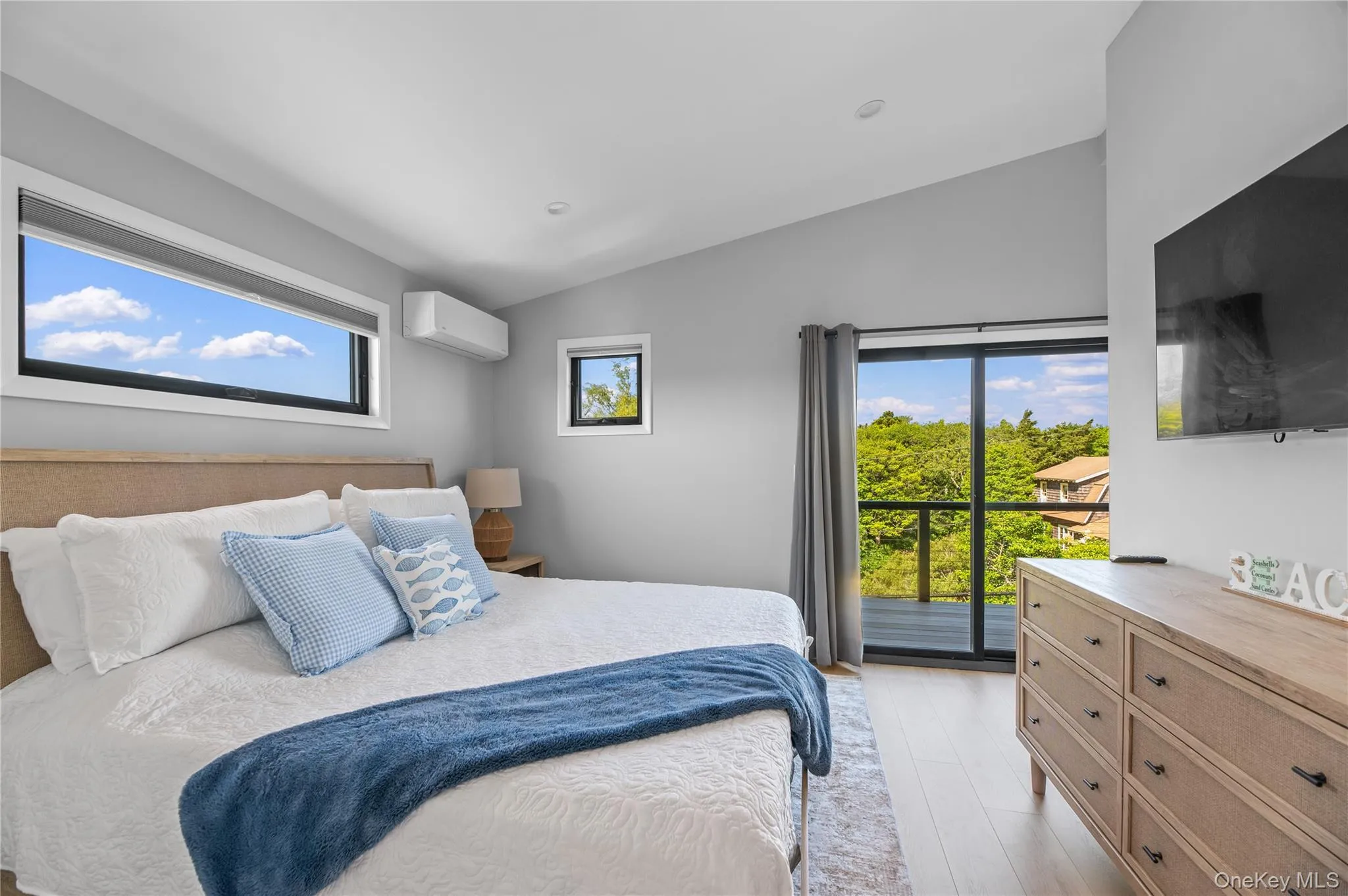 Bedroom with vaulted ceiling, light wood finished floors, a wall mounted AC, and access to outside Bedroom with vaulted ceiling, light wood finished floors, a wall mounted AC, and access to outside