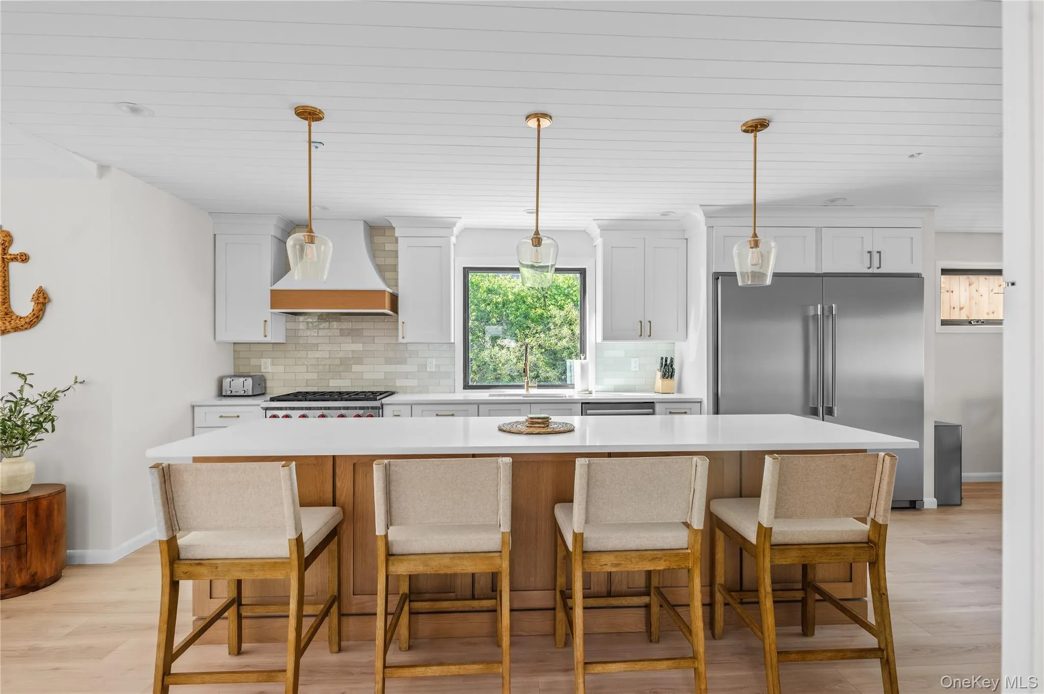 Kitchen featuring decorative backsplash, high end fridge, a kitchen island, light wood-style floors, and a kitchen bar Kitchen featuring decorative backsplash, high end fridge, a kitchen island, light wood-style floors, and a kitchen bar
