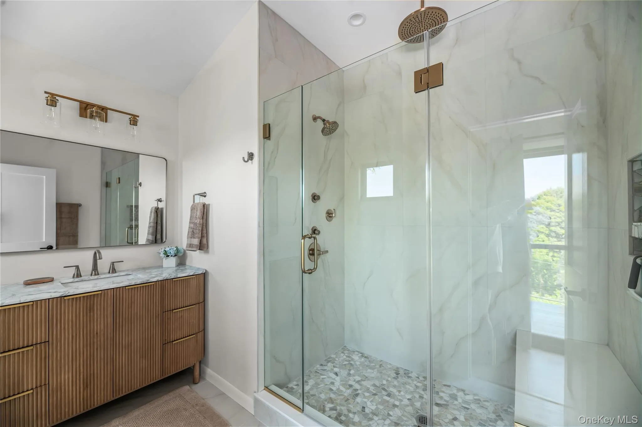 Bathroom with a marble finish shower, vanity, and light tile patterned floors Bathroom with a marble finish shower, vanity, and light tile patterned floors