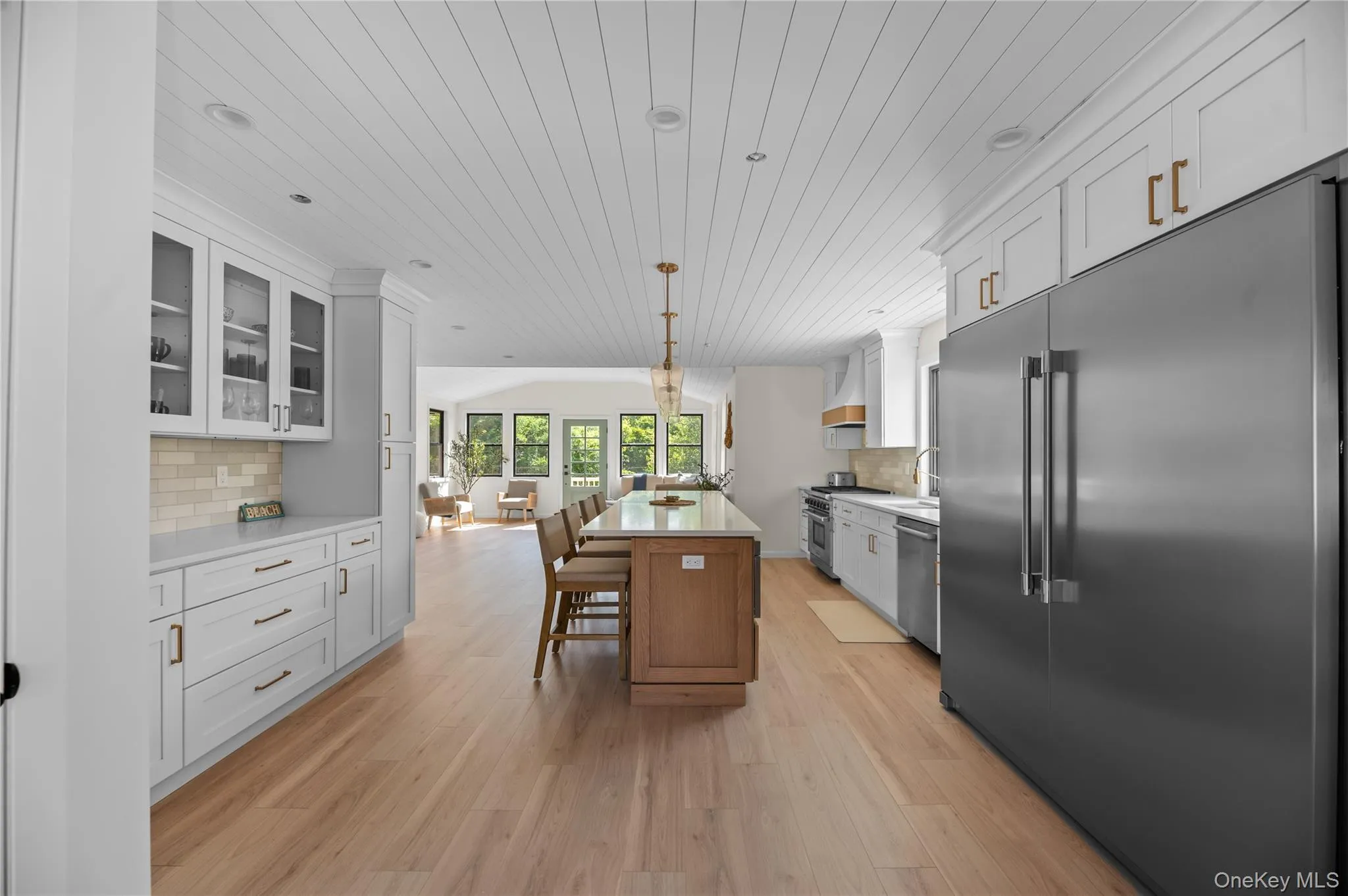 Kitchen with backsplash, premium appliances, wooden ceiling, glass insert cabinets, and open floor plan Kitchen with backsplash, premium appliances, wooden ceiling, glass insert cabinets, and open floor plan