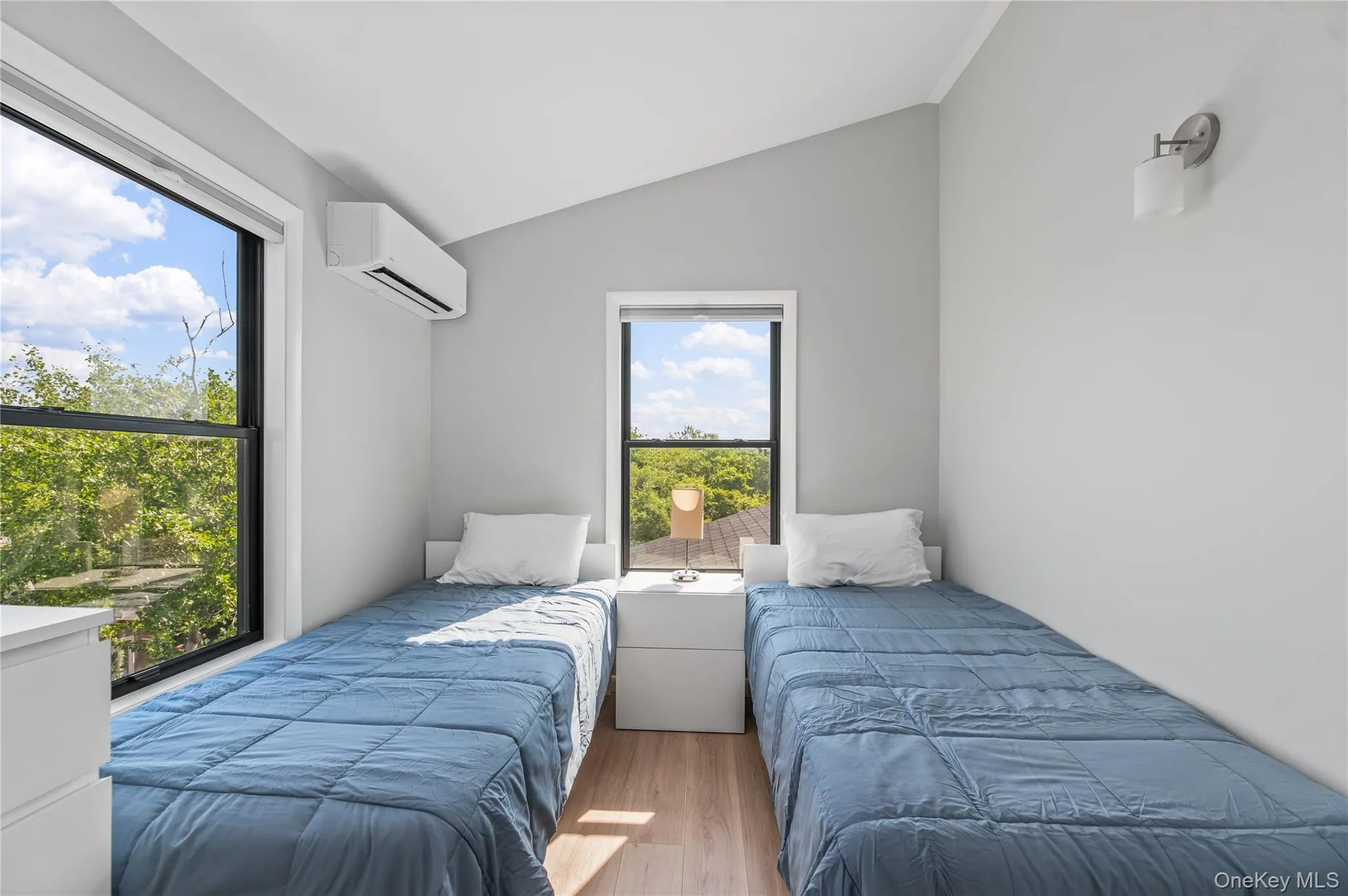 Bedroom featuring vaulted ceiling, wood finished floors, and a wall mounted AC Bedroom featuring vaulted ceiling, wood finished floors, and a wall mounted AC