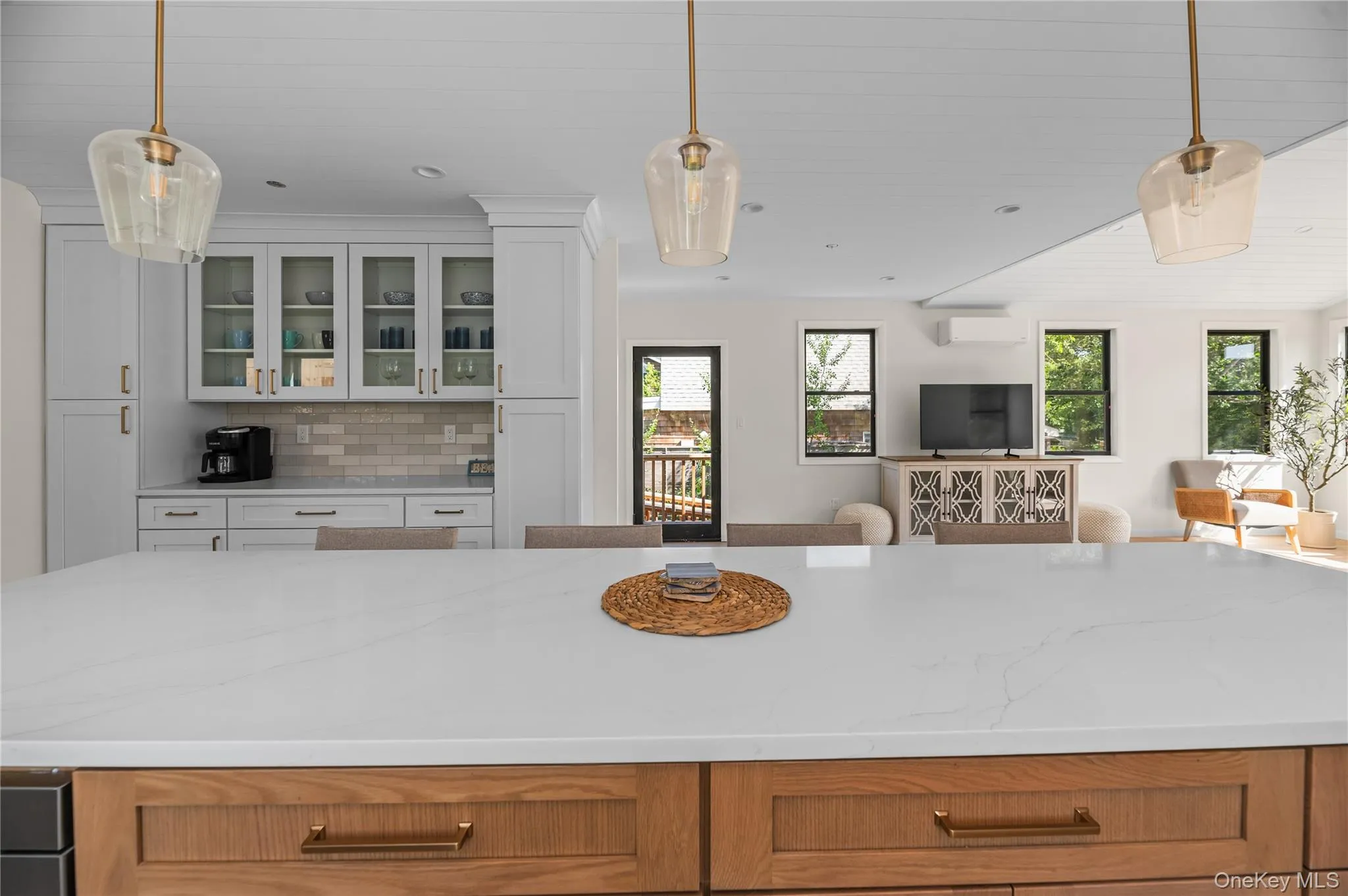 Kitchen featuring pendant lighting, backsplash, open floor plan, and glass insert cabinets Kitchen featuring pendant lighting, backsplash, open floor plan, and glass insert cabinets