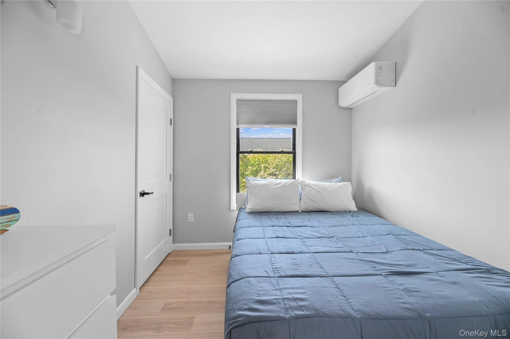 Bedroom with light wood-style floors and an AC wall unit Bedroom with light wood-style floors and an AC wall unit