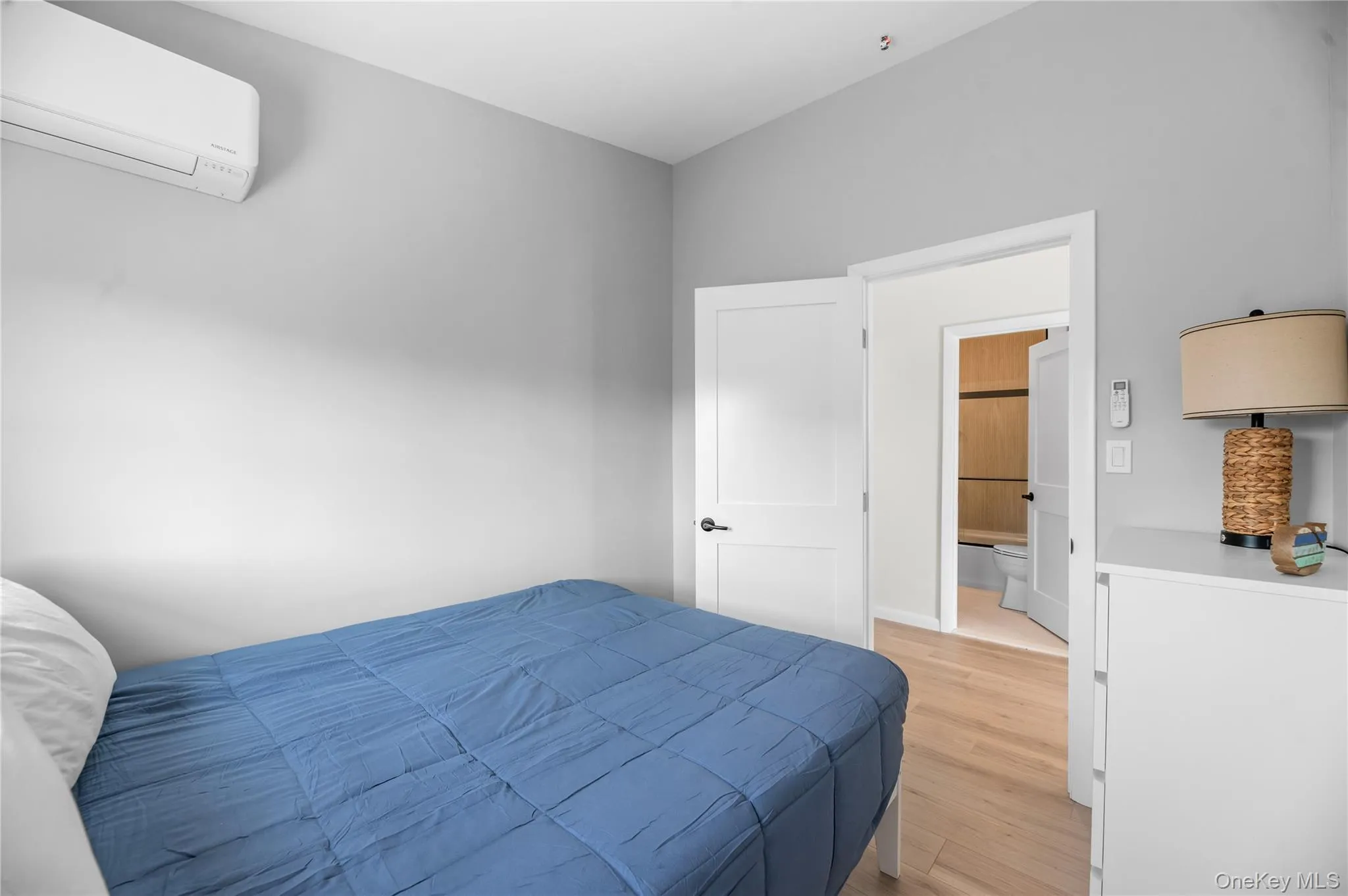 Bedroom with a wall mounted air conditioner and light wood-style floors Bedroom with a wall mounted air conditioner and light wood-style floors