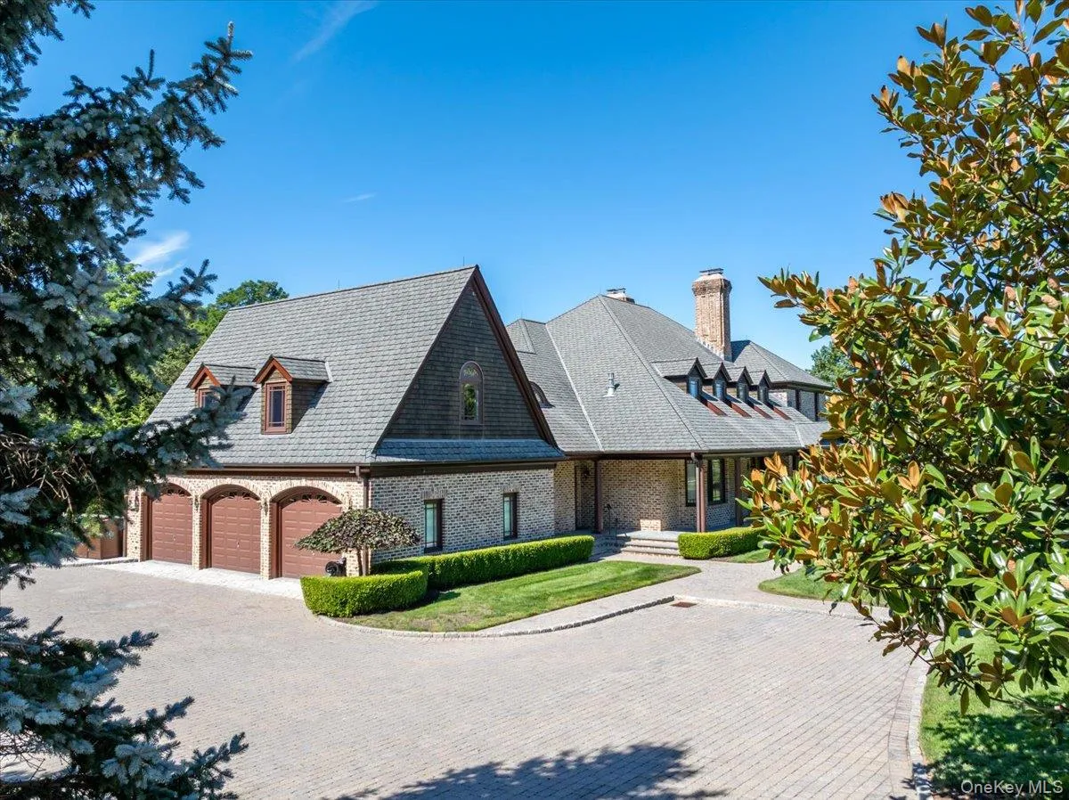View of front facade with decorative driveway, brick siding, a garage, a chimney, and a patio area View of front facade with decorative driveway, brick siding, a garage, a chimney, and a patio area