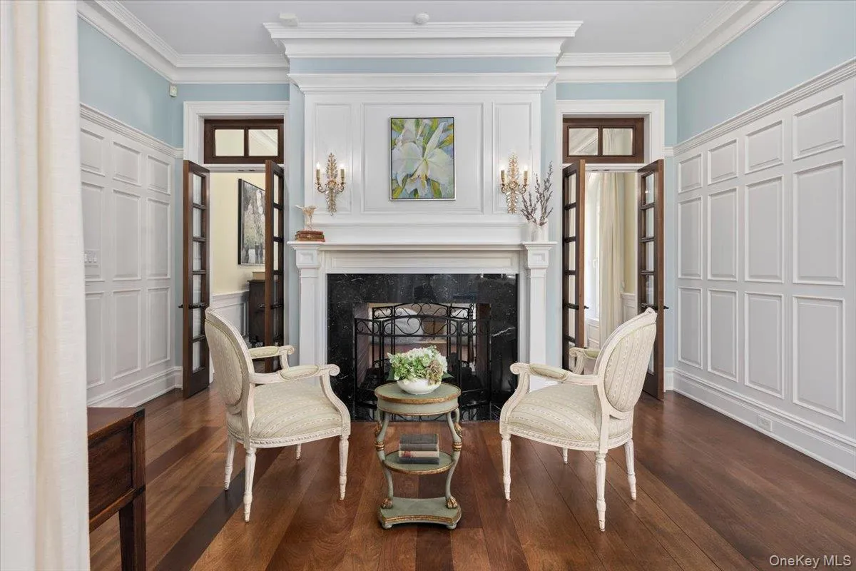 Living area featuring ornamental molding, dark wood finished floors, a high end fireplace, and a decorative wall Living area featuring ornamental molding, dark wood finished floors, a high end fireplace, and a decorative wall
