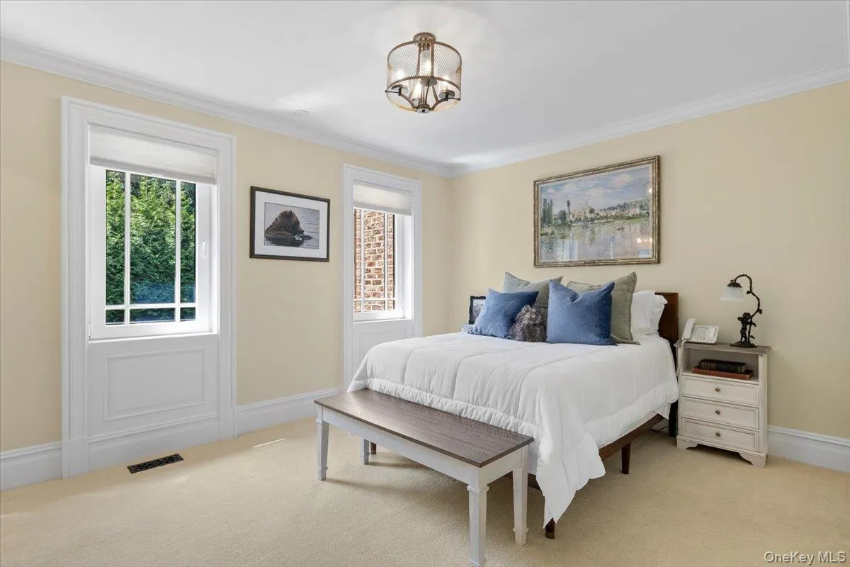 Carpeted bedroom with multiple windows, crown molding, and a chandelier Carpeted bedroom with multiple windows, crown molding, and a chandelier