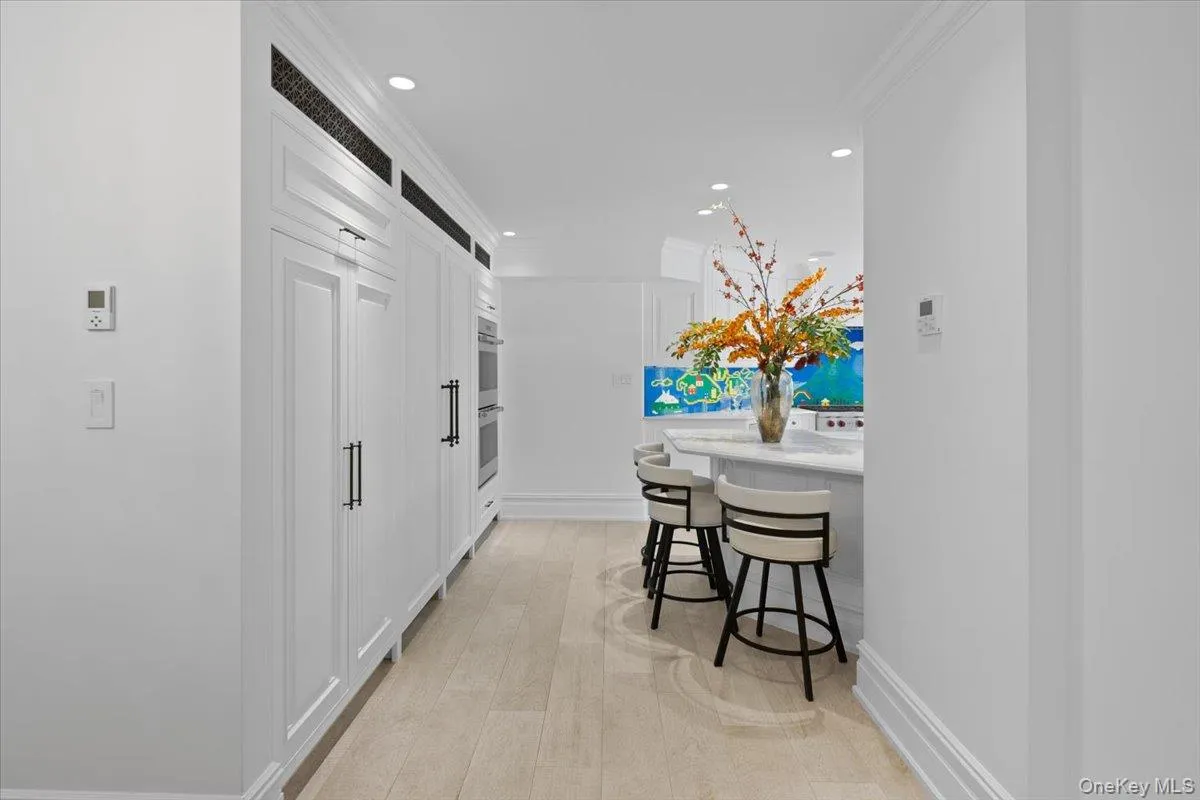 Hallway featuring recessed lighting, ornamental molding, and light wood finished floors Hallway featuring recessed lighting, ornamental molding, and light wood finished floors
