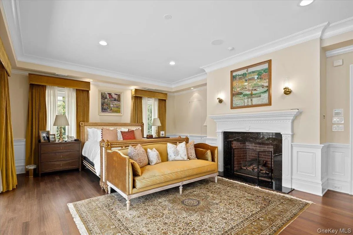 Bedroom with ornamental molding, a decorative wall, a wainscoted wall, a fireplace, and dark wood finished floors Bedroom with ornamental molding, a decorative wall, a wainscoted wall, a fireplace, and dark wood finished floors