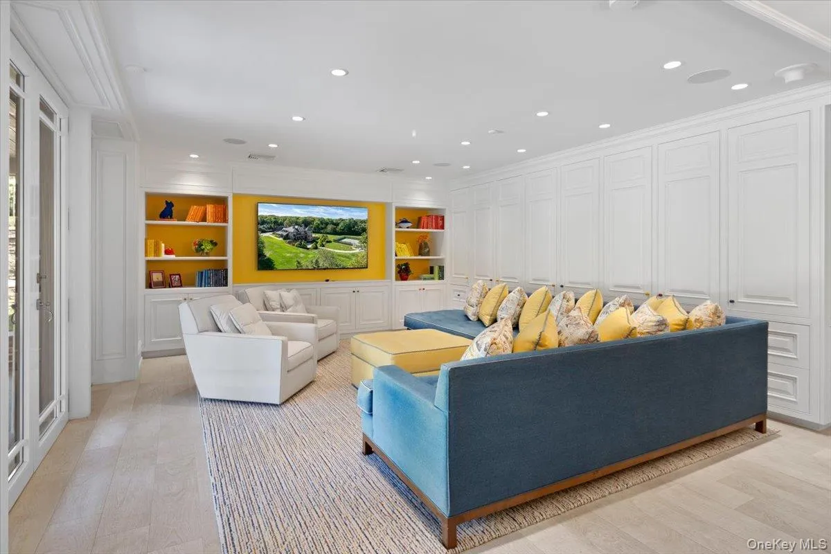 Living area featuring ornamental molding, recessed lighting, built in shelves, light wood-style floors, and a decorative wall Living area featuring ornamental molding, recessed lighting, built in shelves, light wood-style floors, and a decorative wall