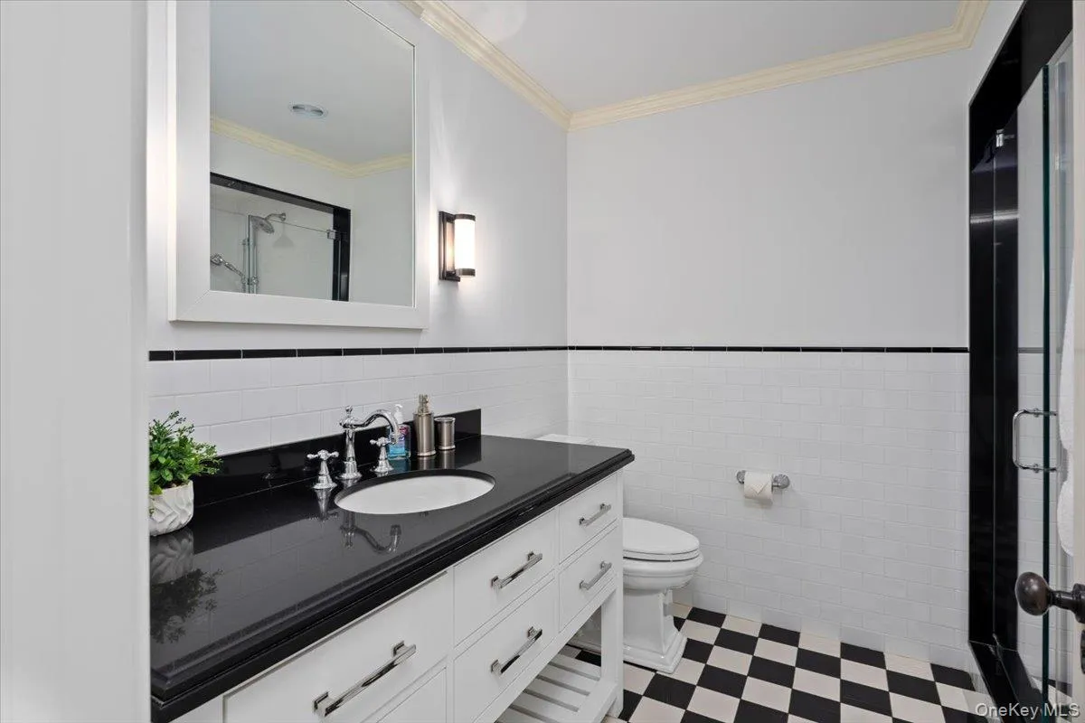 Full bathroom featuring ornamental molding, vanity, a stall shower, tile walls, and a wainscoted wall Full bathroom featuring ornamental molding, vanity, a stall shower, tile walls, and a wainscoted wall
