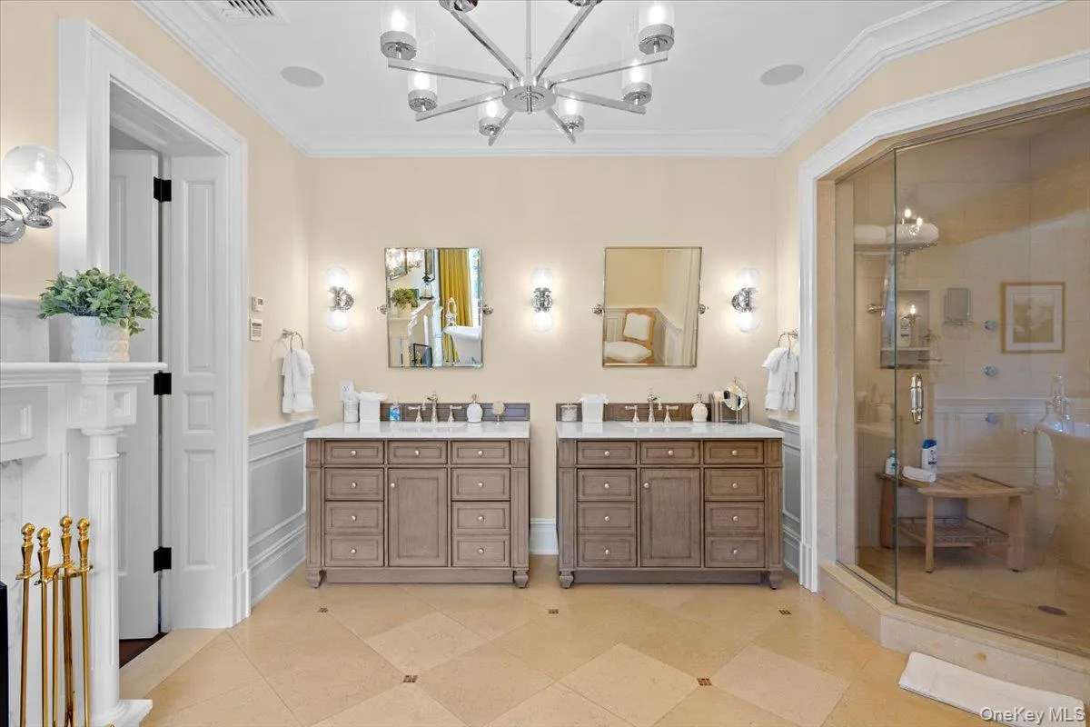 Full bathroom featuring crown molding, a shower stall, vanity, a chandelier, and light tile patterned floors Full bathroom featuring crown molding, a shower stall, vanity, a chandelier, and light tile patterned floors
