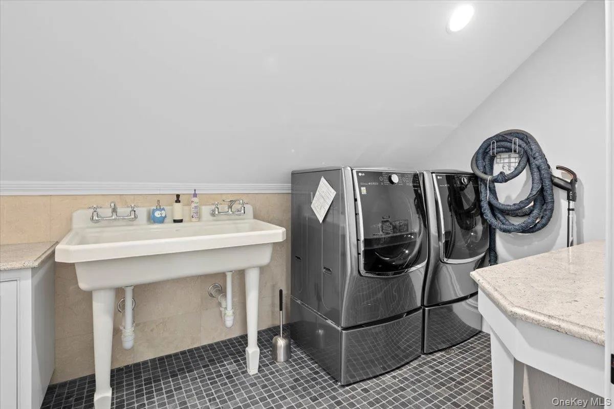 Washroom with dark tile patterned flooring and washing machine and clothes dryer Washroom with dark tile patterned flooring and washing machine and clothes dryer