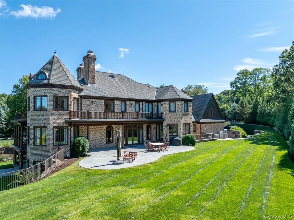 Back of house with a patio area, a chimney, brick siding, a balcony, and an outdoor fire pit Back of house with a patio area, a chimney, brick siding, a balcony, and an outdoor fire pit