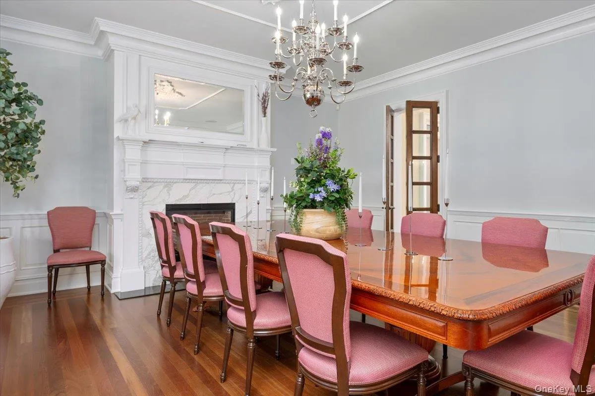 Dining area with a decorative wall, a wainscoted wall, a high end fireplace, crown molding, and dark wood-style flooring Dining area with a decorative wall, a wainscoted wall, a high end fireplace, crown molding, and dark wood-style flooring