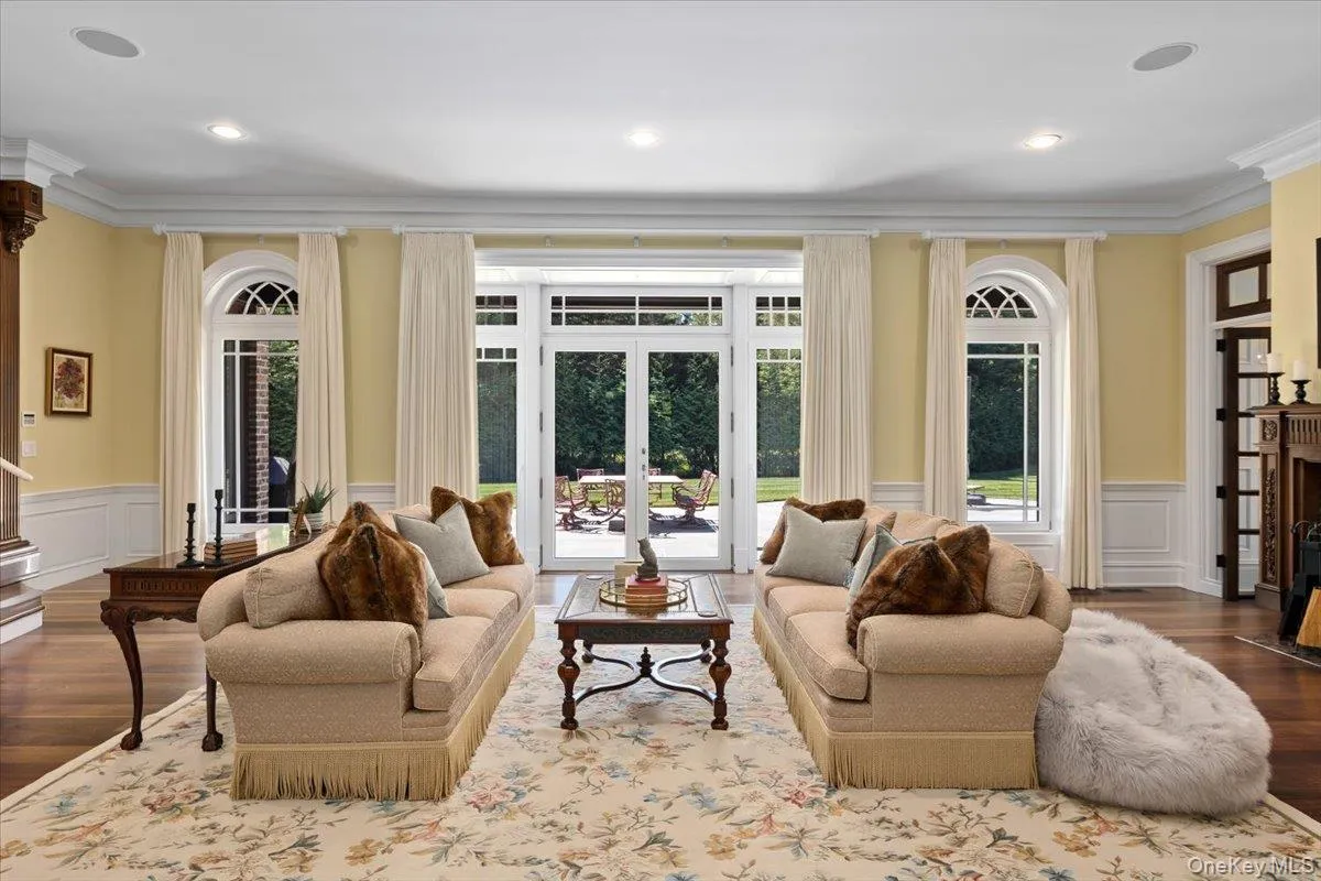 Living area featuring wood finished floors, a wainscoted wall, a decorative wall, crown molding, and a fireplace Living area featuring wood finished floors, a wainscoted wall, a decorative wall, crown molding, and a fireplace