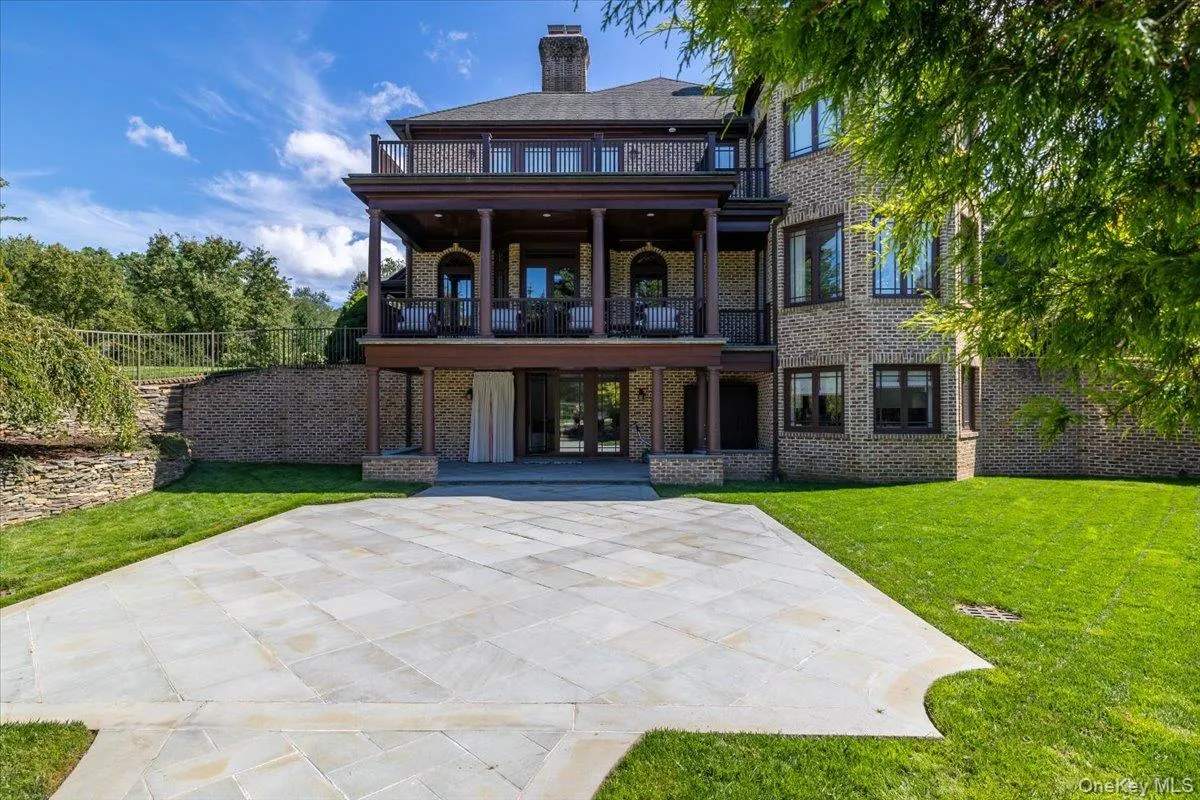 Back of house with brick siding, a balcony, a lawn, and a chimney Back of house with brick siding, a balcony, a lawn, and a chimney