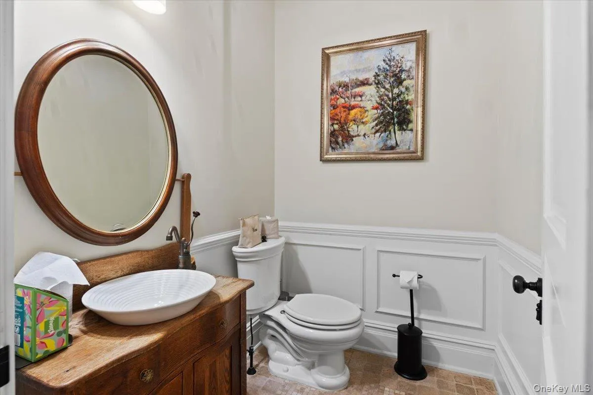 Half bath featuring a decorative wall, vanity, and a wainscoted wall Half bath featuring a decorative wall, vanity, and a wainscoted wall