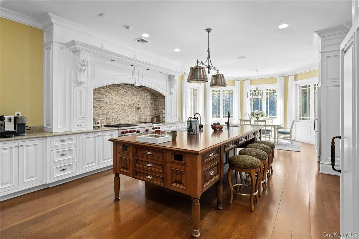 Kitchen with backsplash, white cabinetry, ornamental molding, light stone countertops, and dark wood finished floors Kitchen with backsplash, white cabinetry, ornamental molding, light stone countertops, and dark wood finished floors