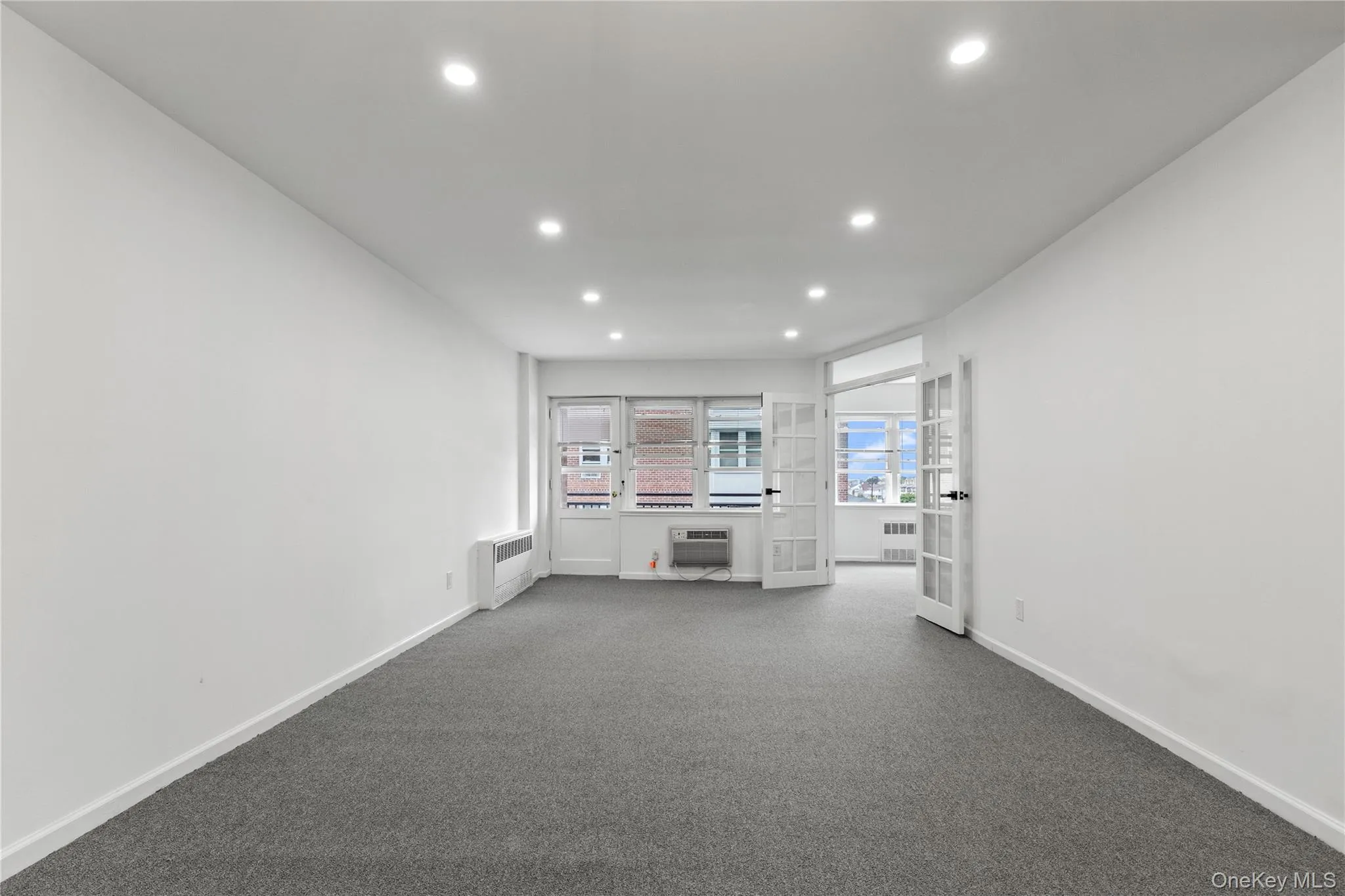 Unfurnished living room with recessed lighting, carpet floors, and radiator Unfurnished living room with recessed lighting, carpet floors, and radiator